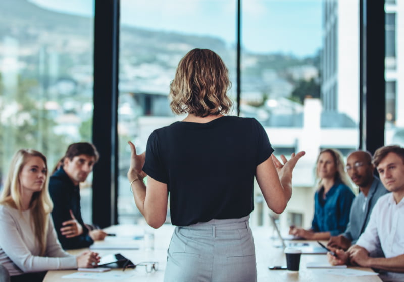 A woman addressing colleagues during a workplace meeting
