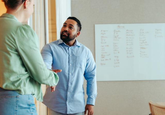 Two colleagues in conversation beside a whiteboard during a mentoring session