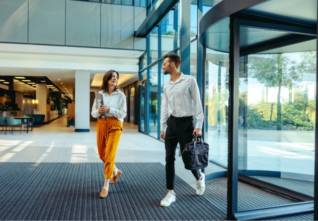 Two early-career colleagues walking together through a modern office lobby