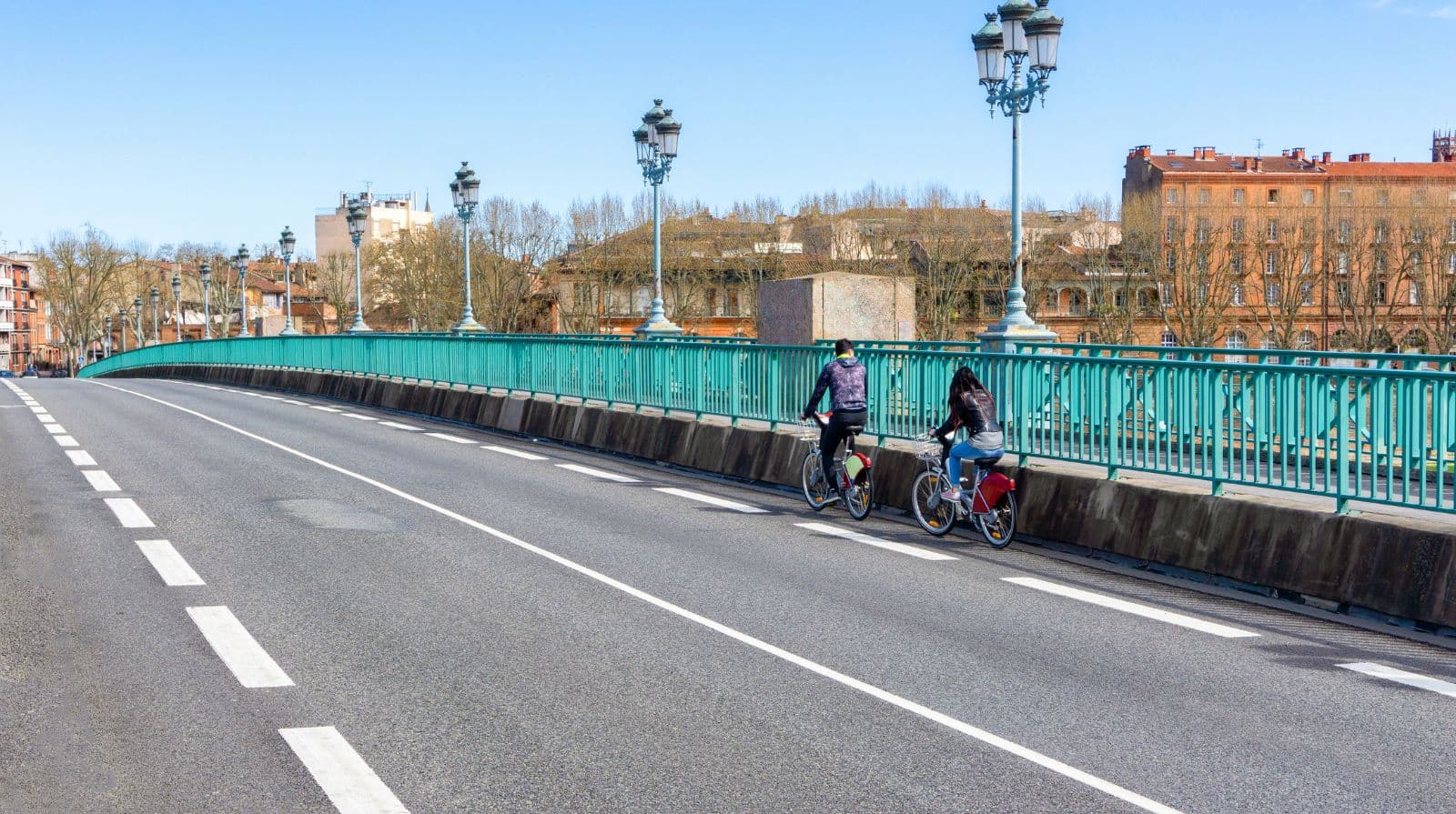 People riding a bicycle in a bike lane safely across a city bridge, Toulouse, France