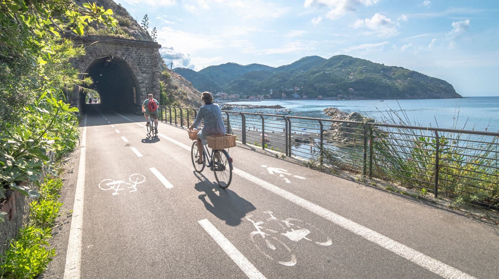 Couple cycling on seaside bike path along the Ligurian coast, Italy