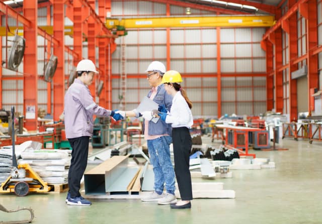 Team of engineering students wearing hard hats discussing plans inside an industrial workshop on a career-readiness visit.