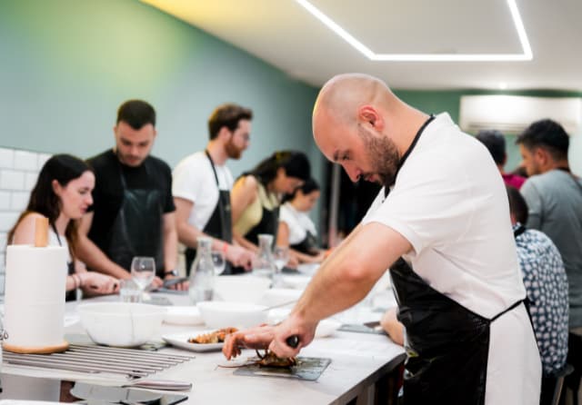 Young students learning to prepare a local dish alongside a chef during an international cooking class.