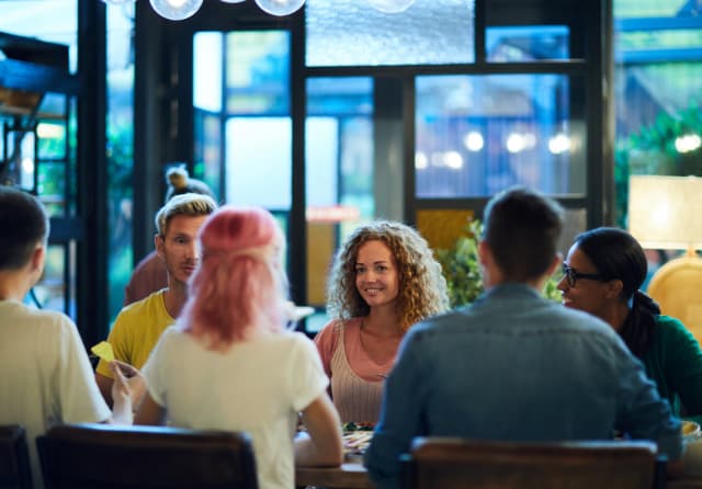 Diverse group of friends laughing and connecting around a cafe table during a study-abroad programme.