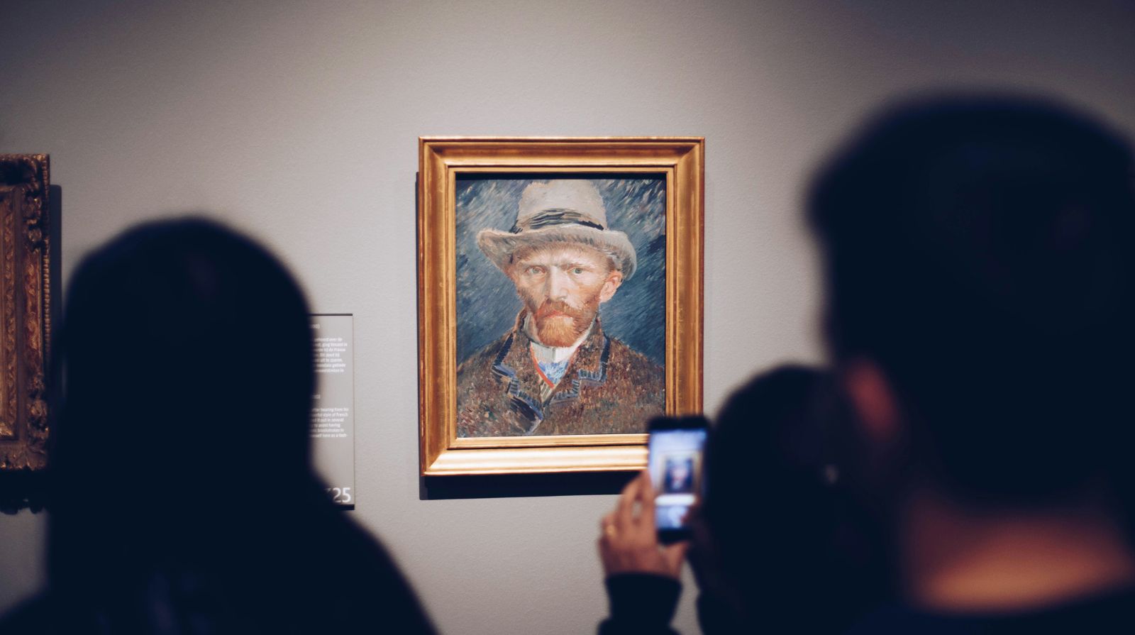 A visitor photographing a portrait painting inside a European art museum.