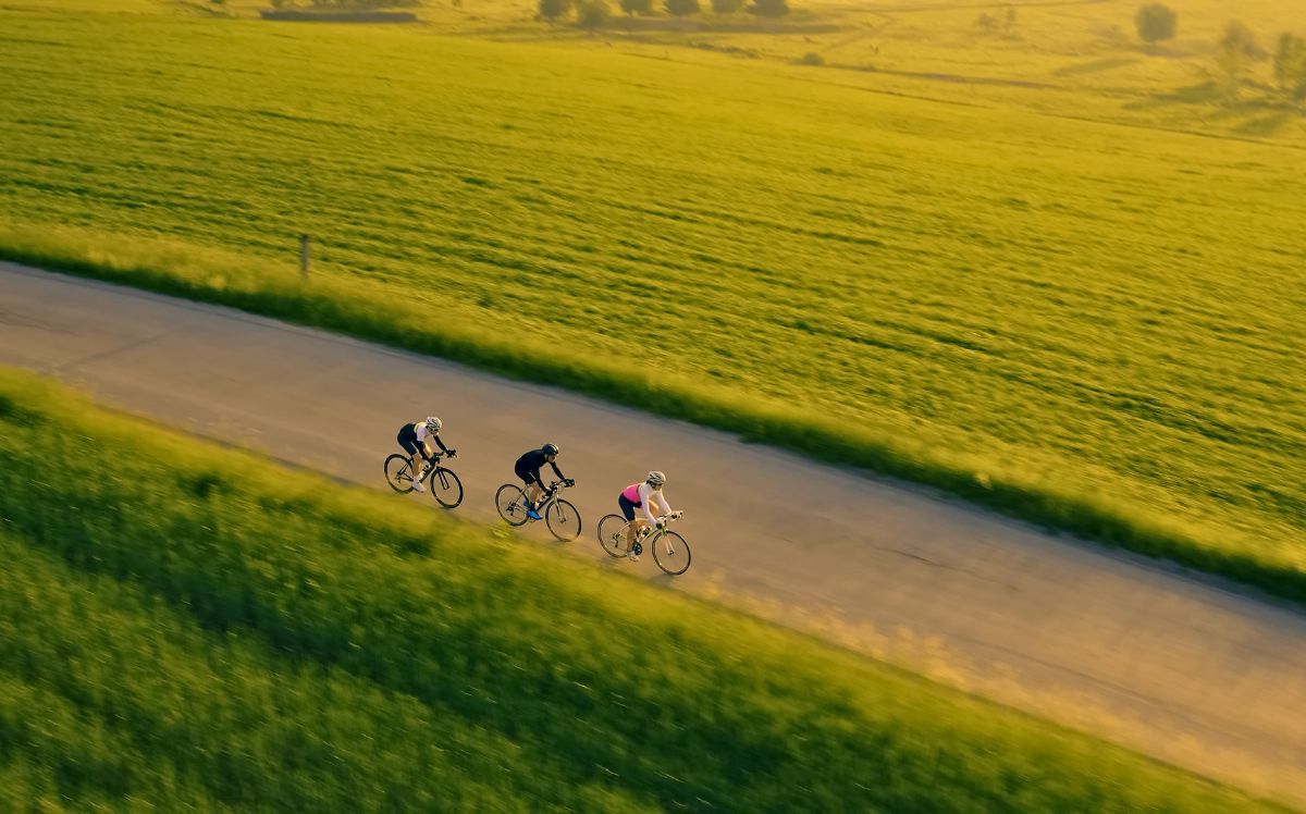 Group of cyclists pedalling down a winding road through a European countryside landscape on a sustainable group travel programme 