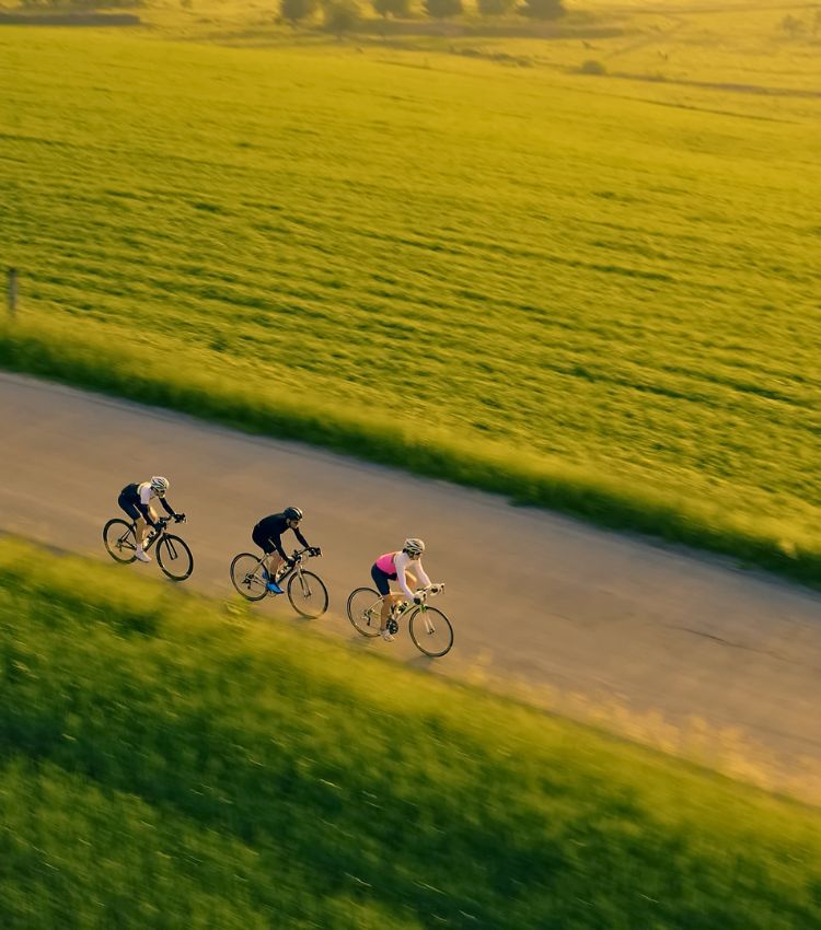Group of cyclists pedalling down a winding road through a European countryside landscape on a sustainable group travel programme 