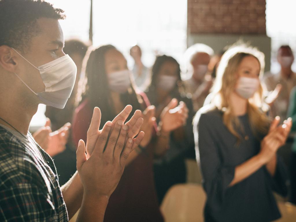 Group of people clapping wearing facemasks