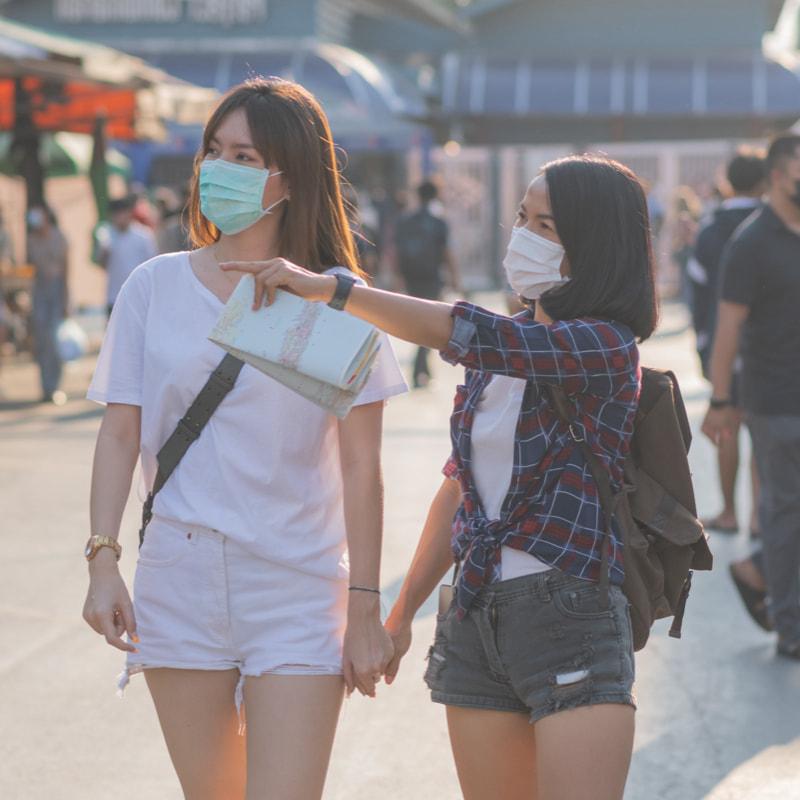 Tourists with a map holding hands and wearing face masks