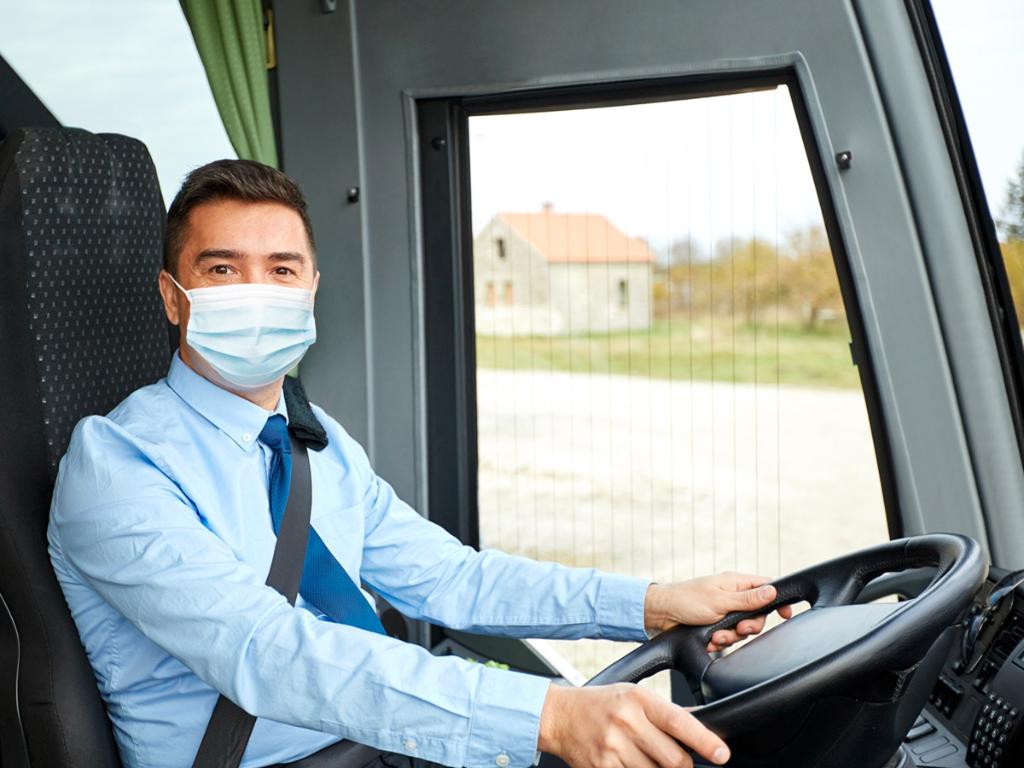 Bus driver in blue shirt wearing a face mask